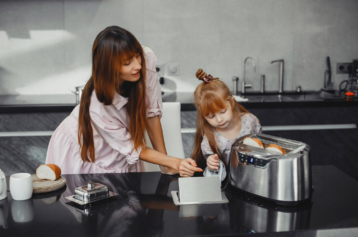 Woman with her daughter using a toaster