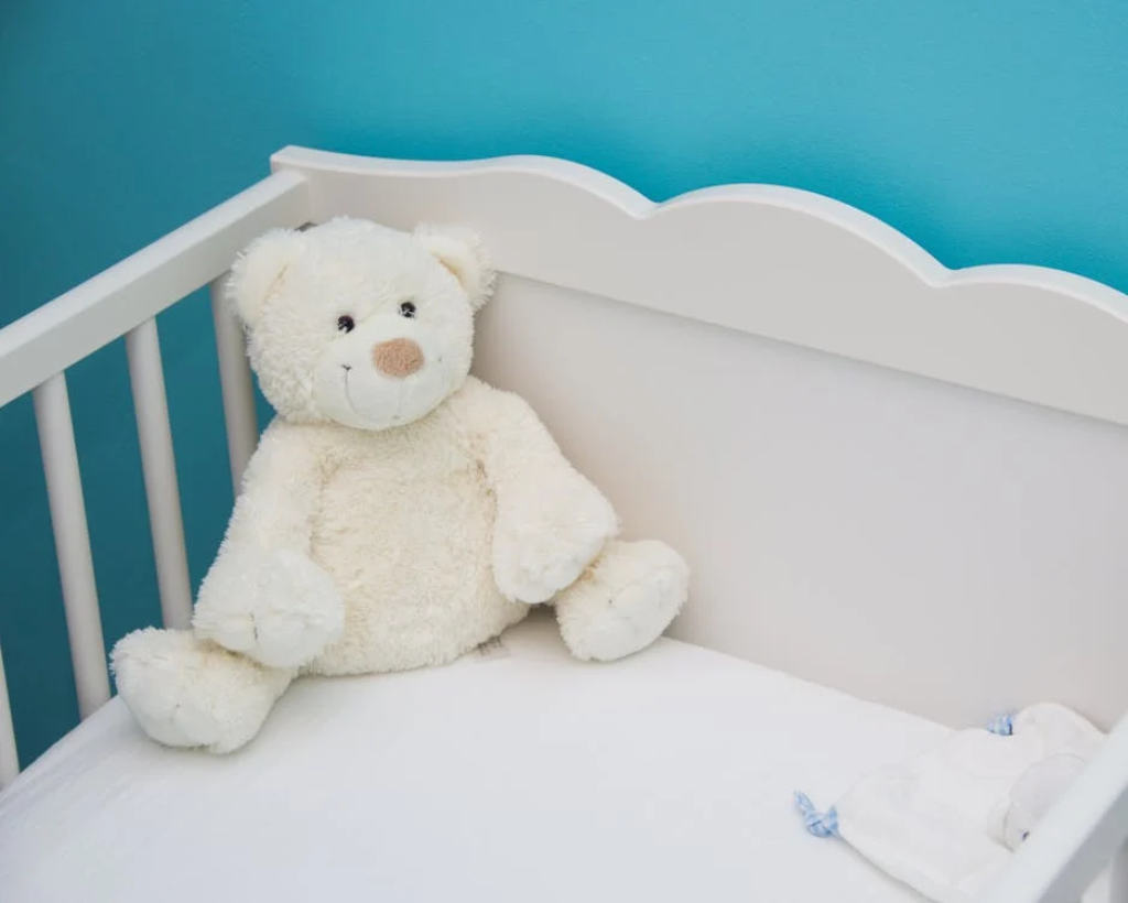 A white bear plush toy in a crib 
