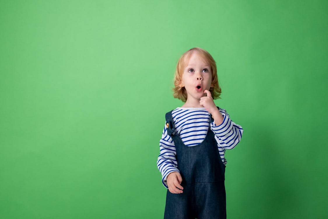 A curious child in front of a green background