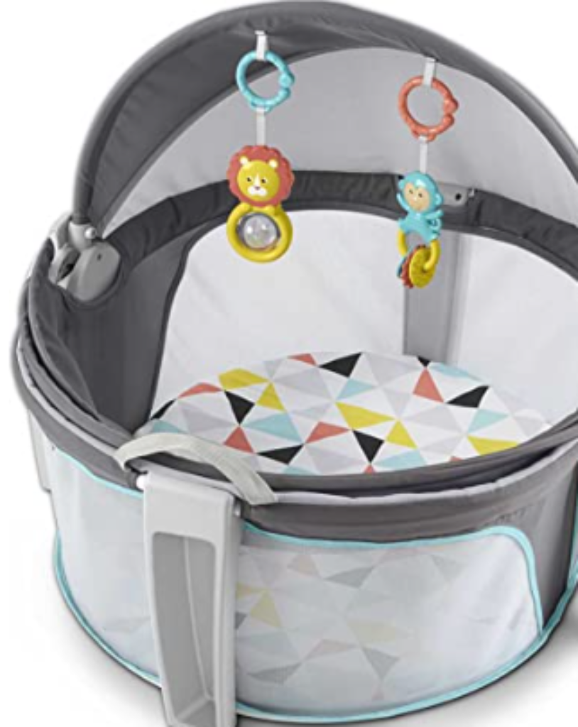 A portable bassinet with canopy and baby toys inside.
Caption: Multi-use bassinet offers comfort, shade, and sensory play for newborns