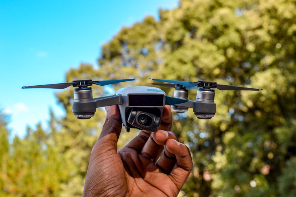 A close-up of a person’s hand holding a compact drone outdoors, ready for launch