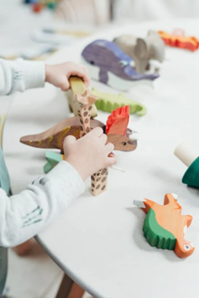 A child playing with wooden animal toys on a table.