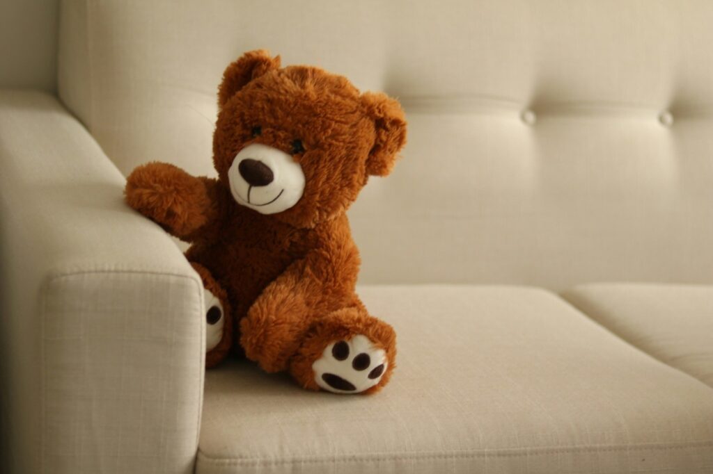 a brown teddy bear on a white couch